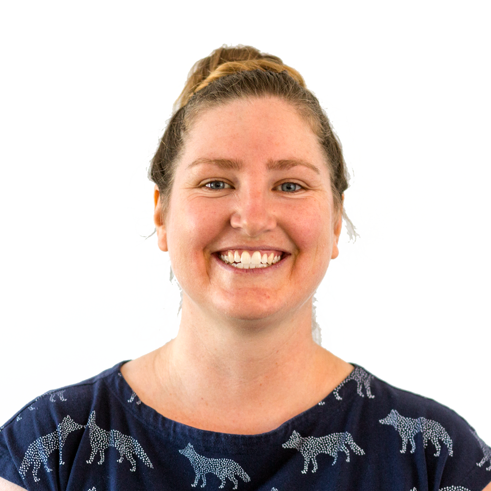 Emily, smiling at the camera with a shirt with a wolf pattern on it. Her hair is pulled up.