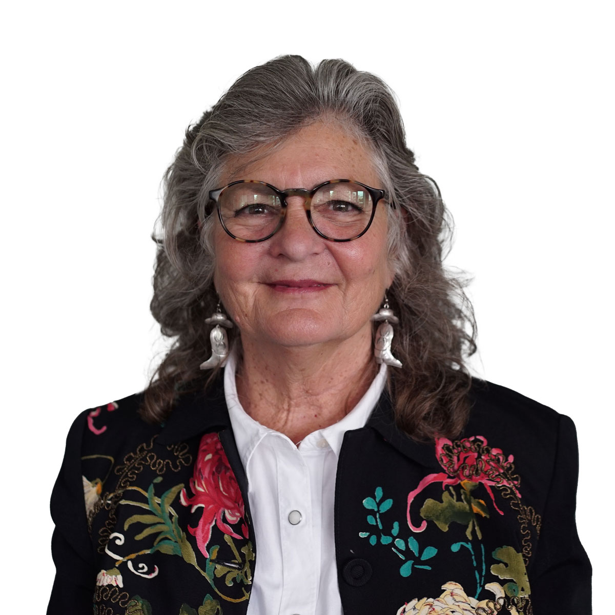 Angel smiling with tortoise shell round glasses, an embroidered black jacket, crisp white shirt with mother of pearl snaps, and silver cowboy earrings