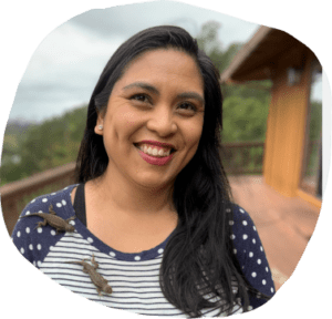 Ileana O.B. smiling on a wood deck overlooking a green forest